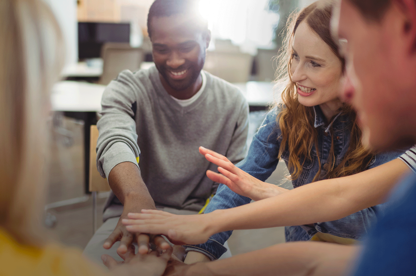 Des personnes souriantes qui rejoignent leurs mains pour travailler ensemble