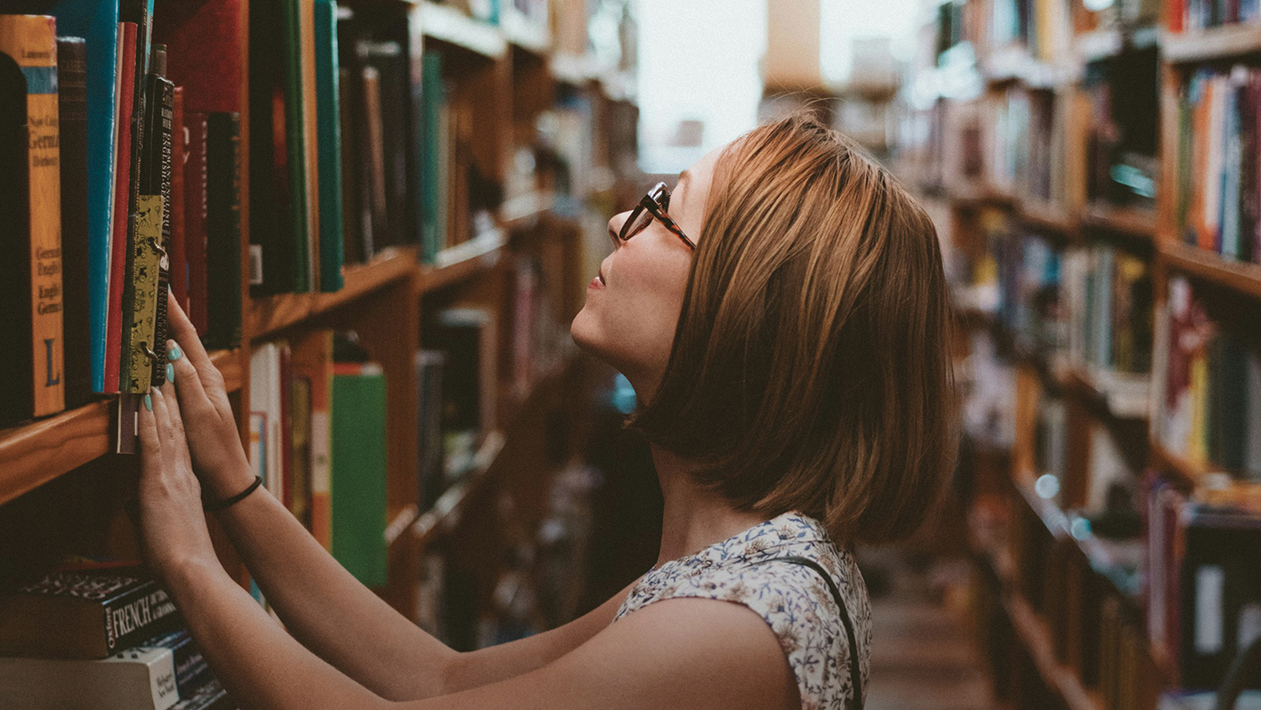 Une étudiante en recherche documentaire dans une bibliothèque